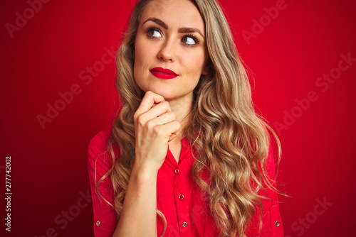 Young beautiful woman standing over red isolated background serious face thinking about question  very confused idea