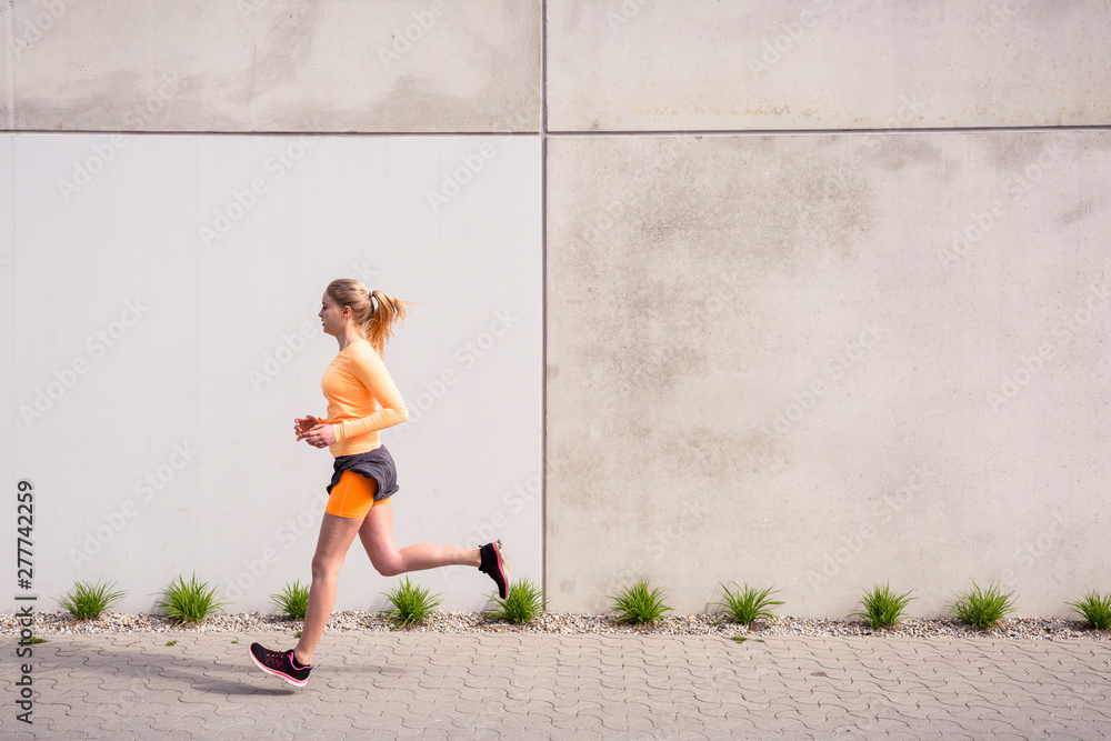 Olympia Park, Munich, Bavaria, Germany: A young female runner running through the olympic village in the morning. Olympia Park, Munich, Bavaria, Germany: A young female runner running through the olympic village in the morning.