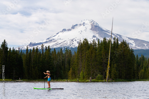 A woman stand up paddleboards at Trillium Lake, a popular recreation spot near the base of Mount Hood, Oregon. photo