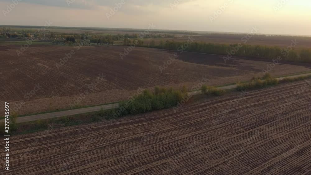 A lone car is fast driving on the farmland field highway. European rural landscape. Aerial survey, flight of drone A lone car is fast driving on the farmland field highway. European rural landscape. Aerial survey, flight of drone