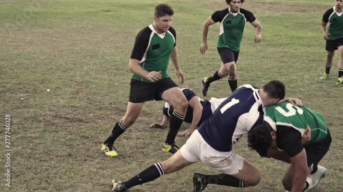 Rugby player with ball tackling the opponent during the match. Rugby players in action on the ground. photo