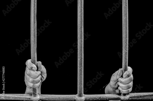 imprisoned in a dark prison holding the bars of a prison cell awaiting justice