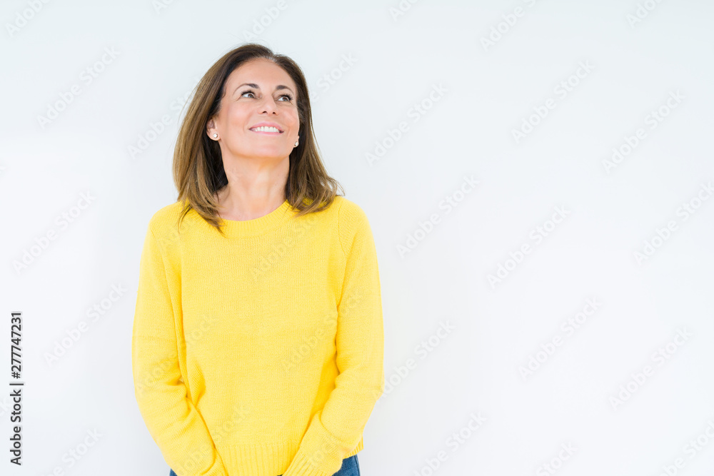 Beautiful middle age woman wearing yellow sweater over isolated background looking away to side with smile on face, natural expression. Laughing confident. Beautiful middle age woman wearing yellow sweater over isolated background looking away to side with smile on face, natural expression. Laughing confident.