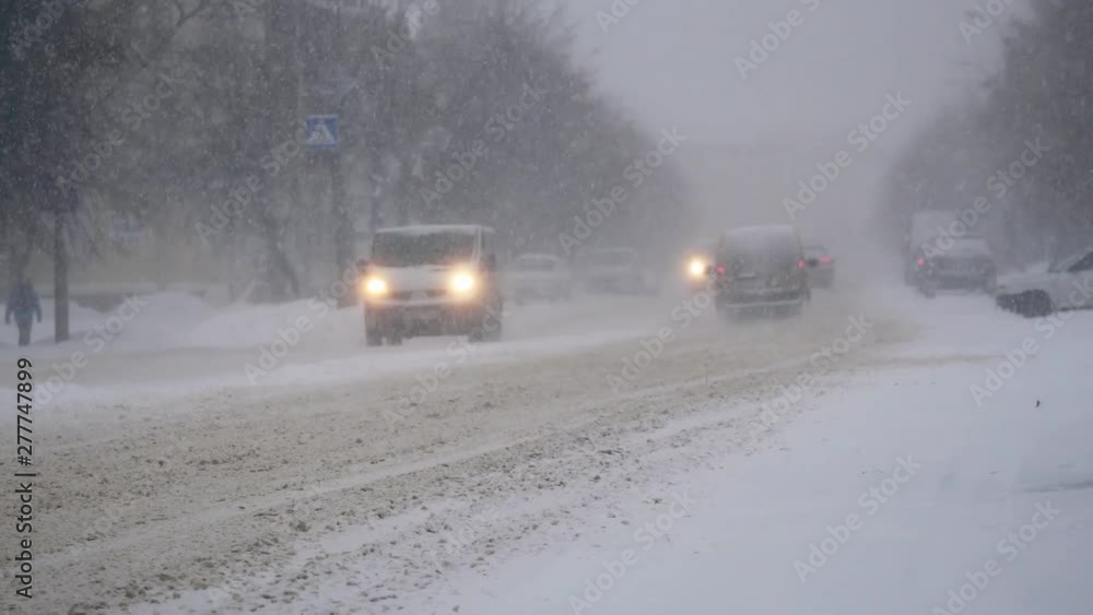 Car urban traffic in the heavy snowstorm blizzard snowfall on the snowy road in the winter city Car urban traffic in the heavy snowstorm blizzard snowfall on the snowy road in the winter city