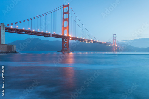 Classic panoramic view of famous Golden Gate Bridge seen from San Francisco harbour in beautiful evening light on a dusk with blue sky and clouds and fog in summer, San Francisco, California, USA © Michal