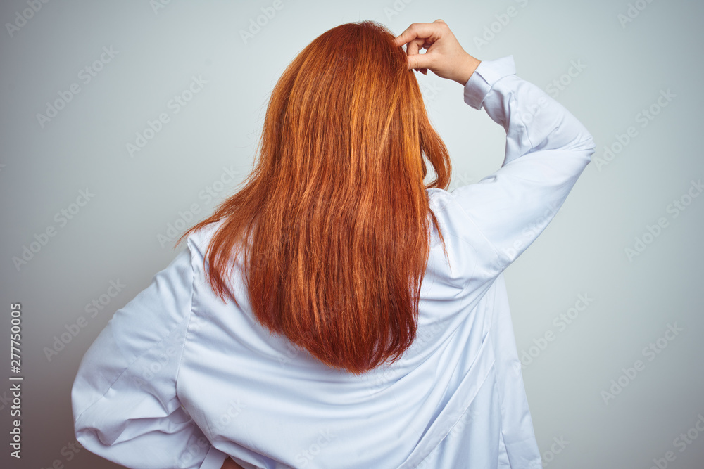 Fototapeta premium Young redhead doctor woman using stethoscope over white isolated background Backwards thinking about doubt with hand on head