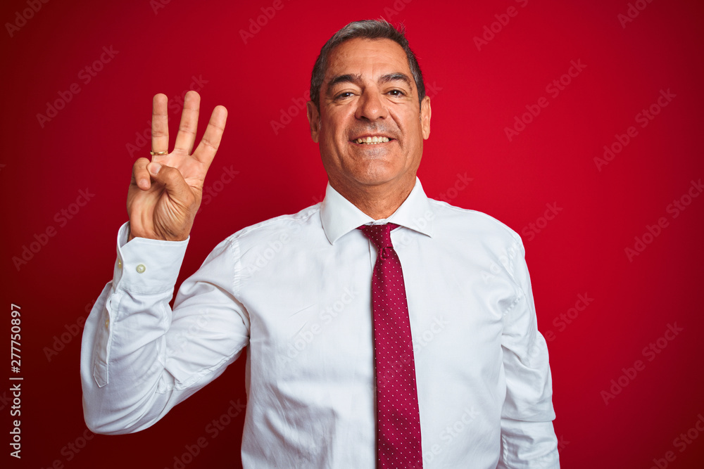 Handsome middle age businessman standing over isolated red background showing and pointing up with fingers number three while smiling confident and happy. Handsome middle age businessman standing over isolated red background showing and pointing up with fingers number three while smiling confident and happy.