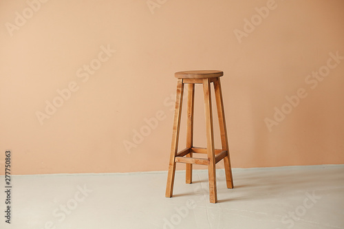 Round wooden stool with beige wall background interior