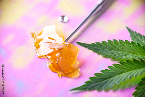 Dab tool with cannabis concentrate aka shatter and marijuana leaf, photo