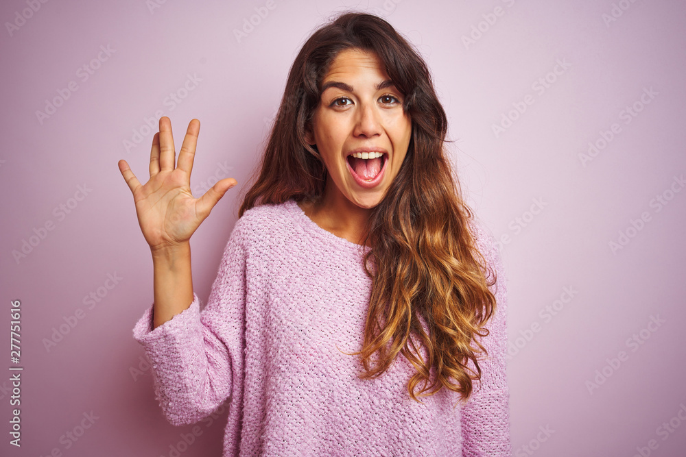 Young beautiful woman wearing sweater standing over pink isolated background showing and pointing up with fingers number five while smiling confident and happy. Young beautiful woman wearing sweater standing over pink isolated background showing and pointing up with fingers number five while smiling confident and happy.