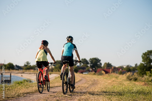 Women on bike riding by the lake shore outdoors at the park