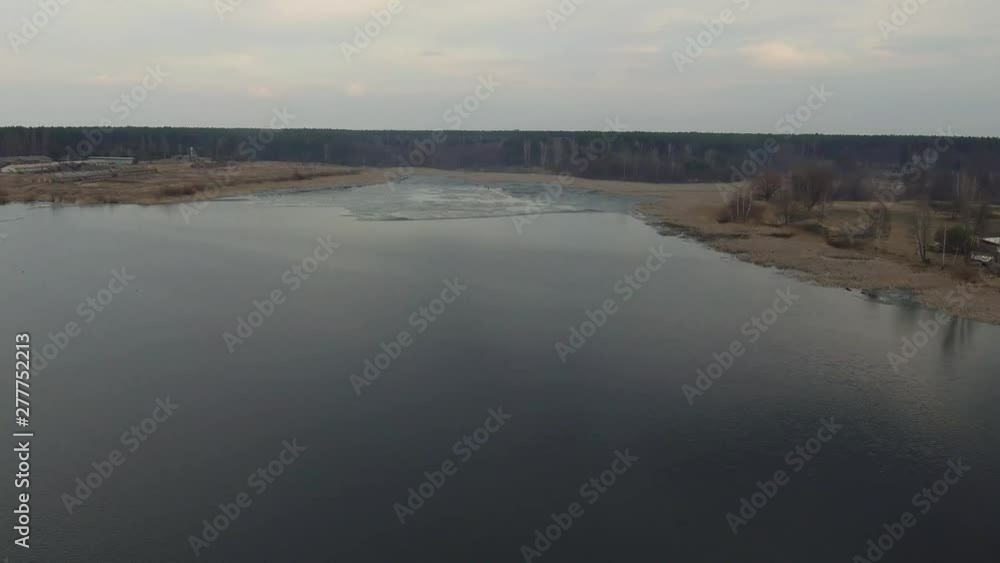 Forest and village on the bank of wide river. Natural water resources and environment of Earth. Aerial survey from air in motion, flight of drone Forest and village on the bank of wide river. Natural water resources and environment of Earth. Aerial survey from air in motion, flight of drone