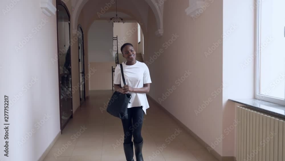 Front view of african student going in corridor after lesson Front view of african student going in corridor after lesson