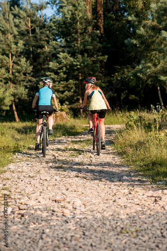 Two women friends riding bikes offroad at the forest