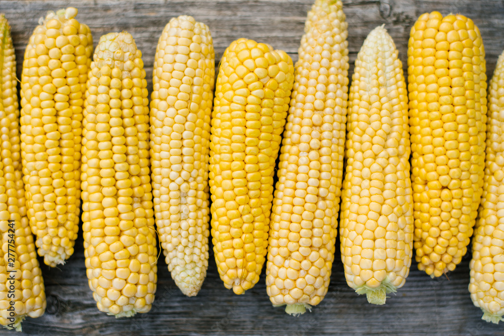 Corn on the old wooden background of organic food store, fresh sweet yellow corn for mass consumption, agricultural products for human consumption