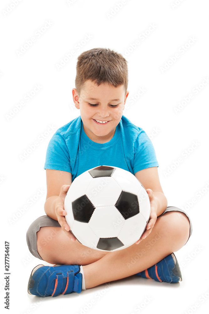 Cute boy is holding a football ball made of genuine leather. Sitting on floor.  Isolated on a white background. Soccer ball