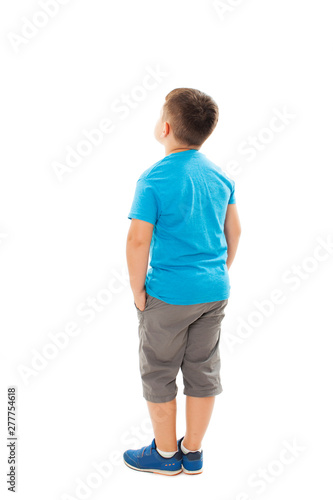 Adorable little boy looking at wall hands in pocket. Rear view, Isolated on white background 