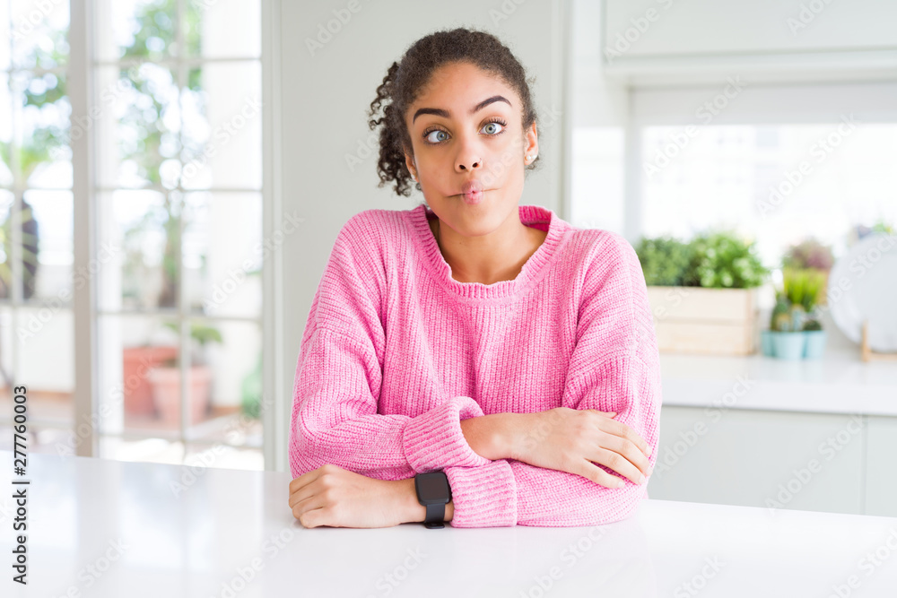 Beautiful african american woman with afro hair wearing casual pink sweater making fish face with lips, crazy and comical gesture. Funny expression. Beautiful african american woman with afro hair wearing casual pink sweater making fish face with lips, crazy and comical gesture. Funny expression.