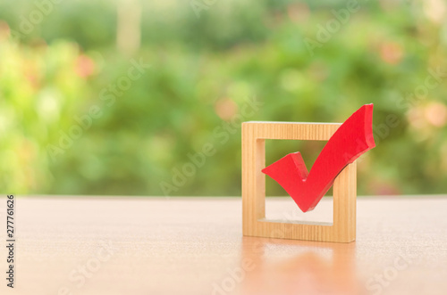 Red wooden checkmark for voting on elections. Presidency or parliamentary elections, a referendum. Survey of the population, statistics, task. Democracy and freedom. Life plans and goals. To do list photo
