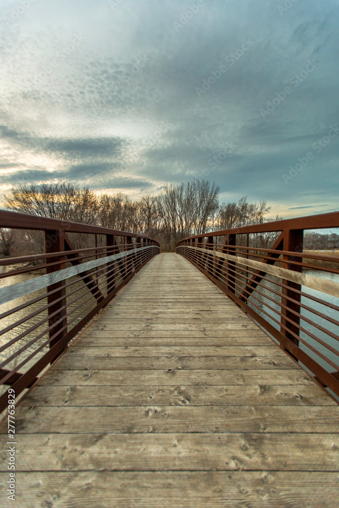Wooden bridge over lake with moody sunset