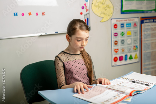 girl learns English through the textbook. Concept - independent study of a foreign language.