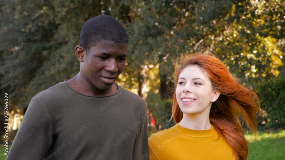 happy smiling mixed couple walking in the park-slow motion happy smiling mixed couple walking in the park-slow motion