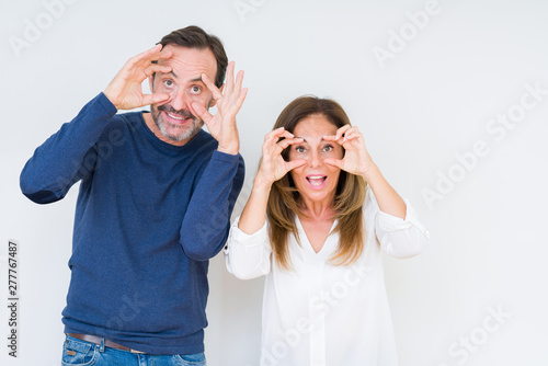 Beautiful middle age couple in love over isolated background Trying to open eyes with fingers, sleepy and tired for morning fatigue