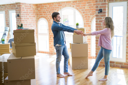 Young couple dancing celebrating moving to new apartment around cardboard boxes © Krakenimages.com