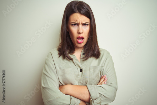 Young beautiful brunette woman wearing green shirt over isolated background skeptic and nervous, disapproving expression on face with crossed arms. Negative person.