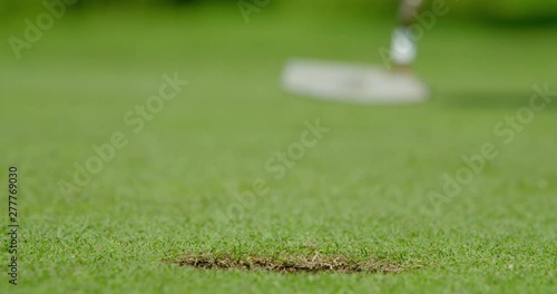 A successful rack focus shot of a golf ball with an alignment line drawn onto the ball to improve accuracy drops into the cup