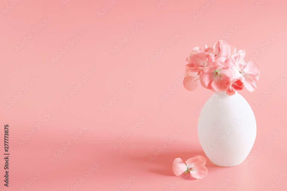 Beautiful flowers composition. Pink flowers in vase on coral color background. copy space