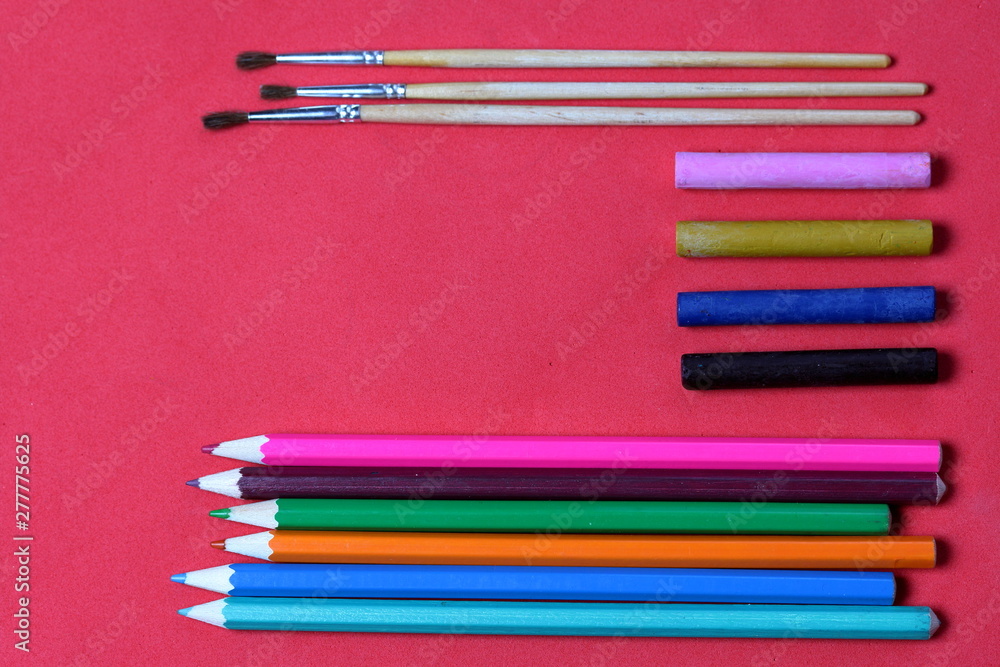 Fototapeta premium Accessories for sketching. Decomposed on the surface of coral color. School supplies.