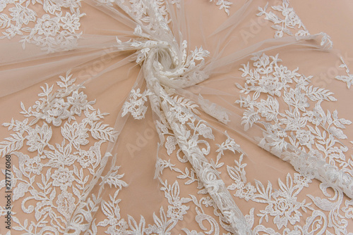 a background image of ivory-colored lace cloth. White lace on beige background.