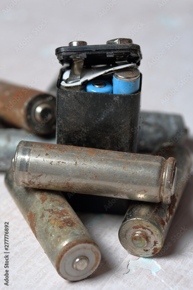 Spent batteries lie on the surface with peeling paint. Covered with corrosion. Recycling and environmental protection.