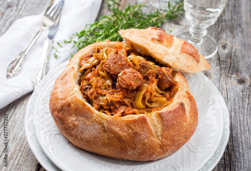 Traditional Polish kraut stew bigos with sausage and meat filled in white bread as closeup on a plate photo