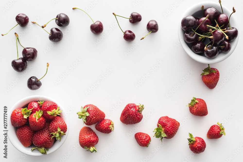 top view of sweet strawberries and fresh cherries on bowls top view of sweet strawberries and fresh cherries on bowls