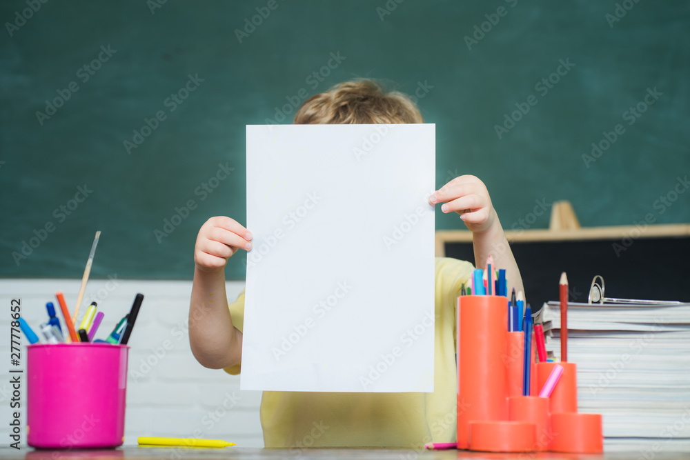 Little boy pupil with happy face expression near desk with school supplies. Teachers day. Teachers day - school concept. Elementary school and education. Little boy pupil with happy face expression near desk with school supplies. Teachers day. Teachers day - school concept. Elementary school and education.