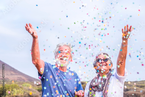 Happy senior couple celebrating with confetti outdoors photo