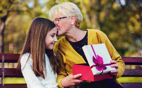 Quadro su tela Grandchild surprised her grandmother with a birthday present in the park