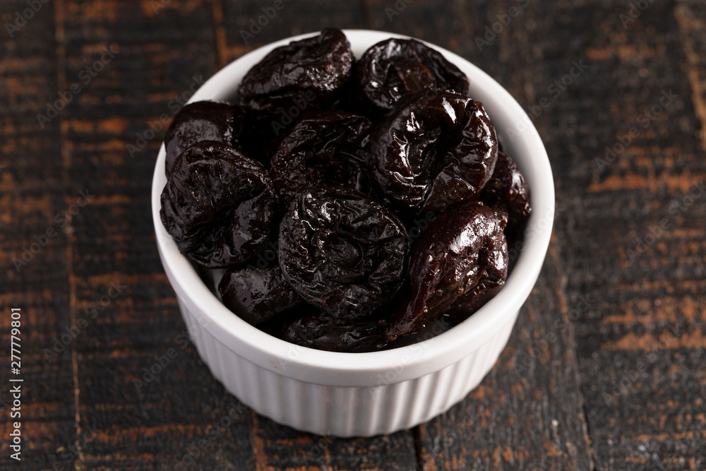 Bowl of Prunes on a Rustic Wooden Table Bowl of Prunes on a Rustic Wooden Table