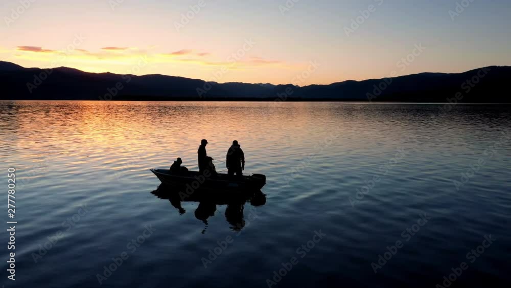 Boat floating on water durning colorful sunset as you view the silhouette of people fishing. Boat floating on water durning colorful sunset as you view the silhouette of people fishing.