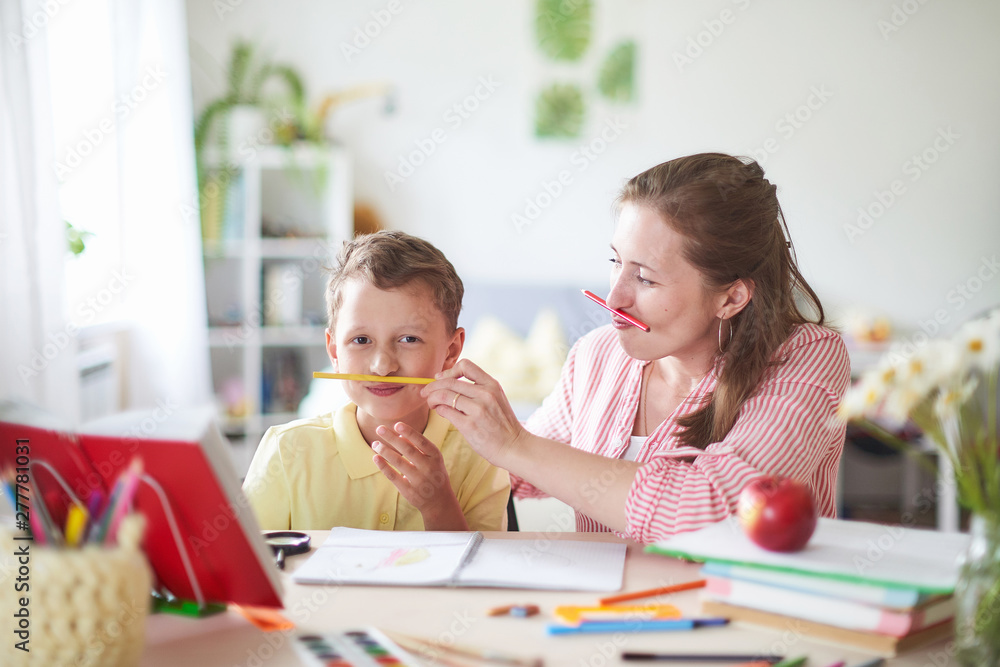 mother helps son to do lessons. home schooling, home lessons. the woman is engaged with the child, checks the job done. outside school classes with parents. mother helps son to do lessons. home schooling, home lessons. the woman is engaged with the child, checks the job done. outside school classes with parents.