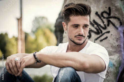 Handsome fit man in white t-shirt outdoor in city setting, looking away