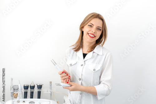Portrait of a young smiling beautiful girl of a professional beautician at the workplace in a white clean office photo