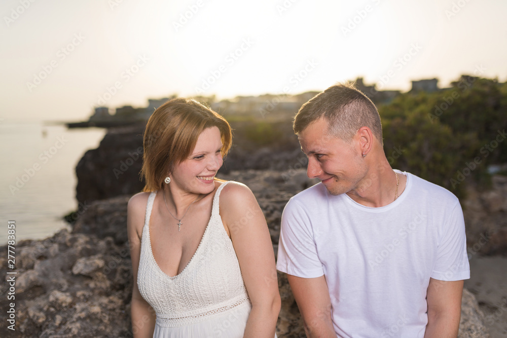 Happy young couple in love smiling by the sea at sunset. Happy young couple in love smiling by the sea at sunset.