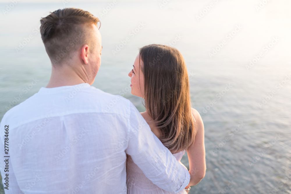 Beach couple looking at ocean view from behind. Relaxing on summer travel vacations in tropical destination Beach couple looking at ocean view from behind. Relaxing on summer travel vacations in tropical destination