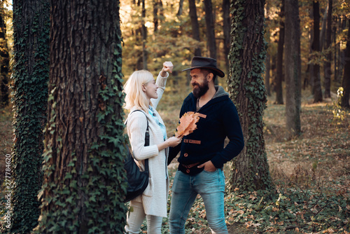 Fashion autumn portrait woman and man with yellow maple leaves on nature background. Autumn outdoor portrait of beautiful happy girl and bearded man walking in park or forest. © Volodymyr