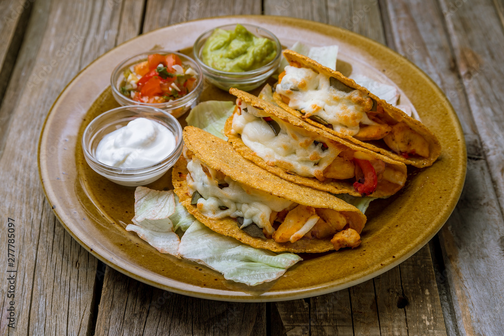 Mexican tacos with chicken with sauses on wooden background