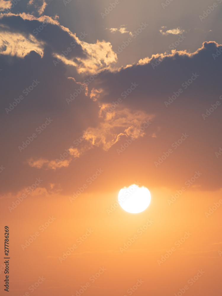 Orange sun setting with clouds above