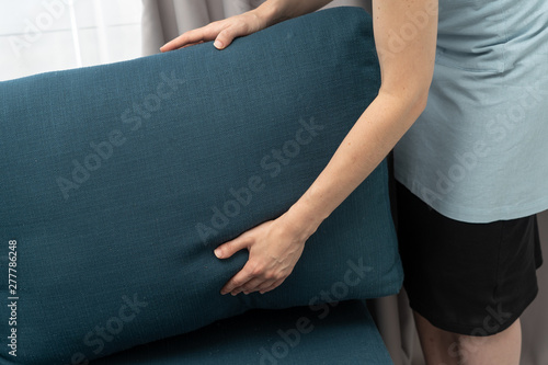 Housemaid woman holding blue couch pillow in hands